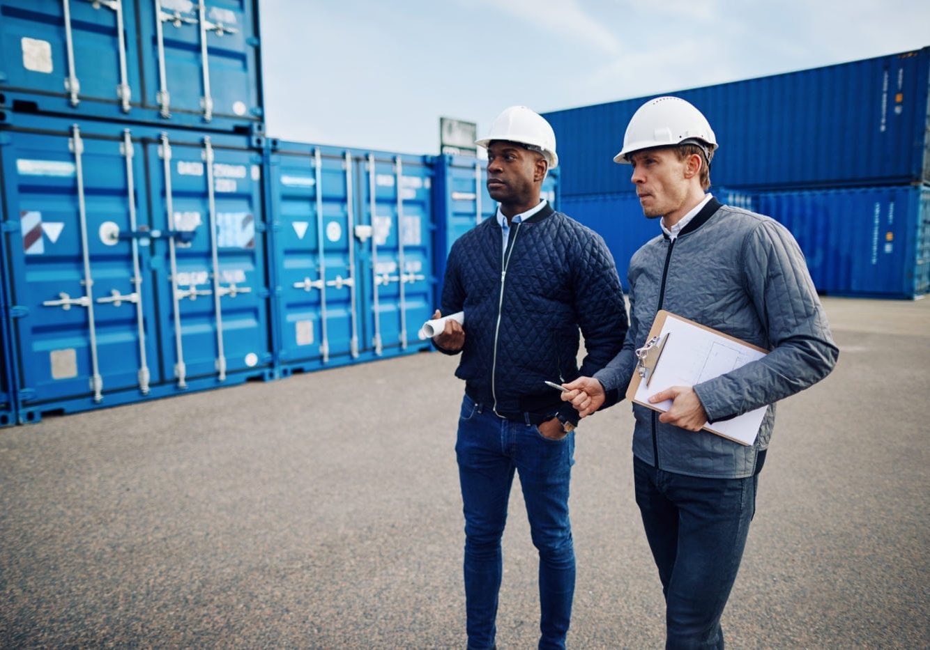 Two engineers discussing logistics in a large shipping yard lean logistics
